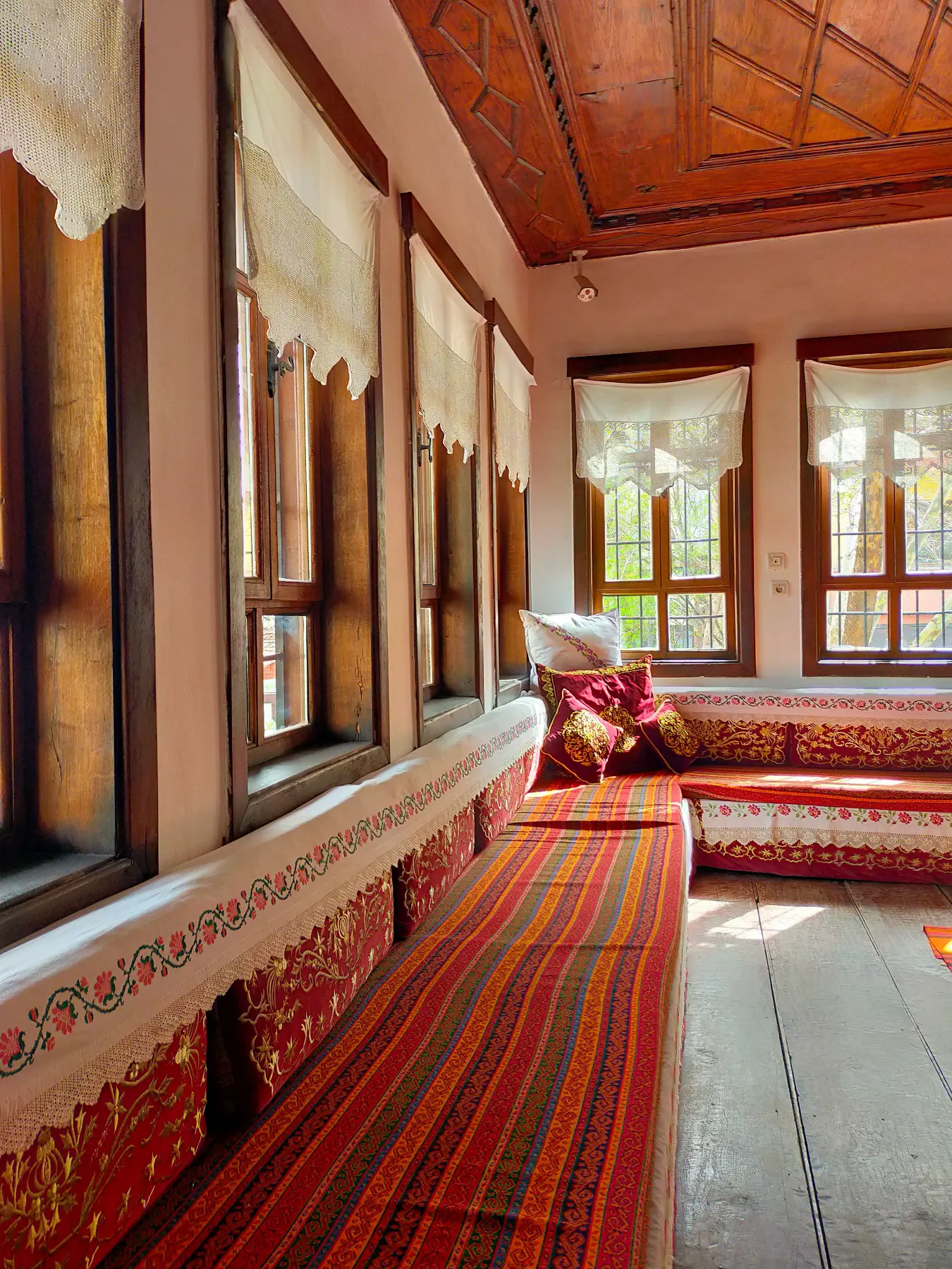 Ahşap konak odasında kilim desenli yer minderleri ve işlemeli örtüler